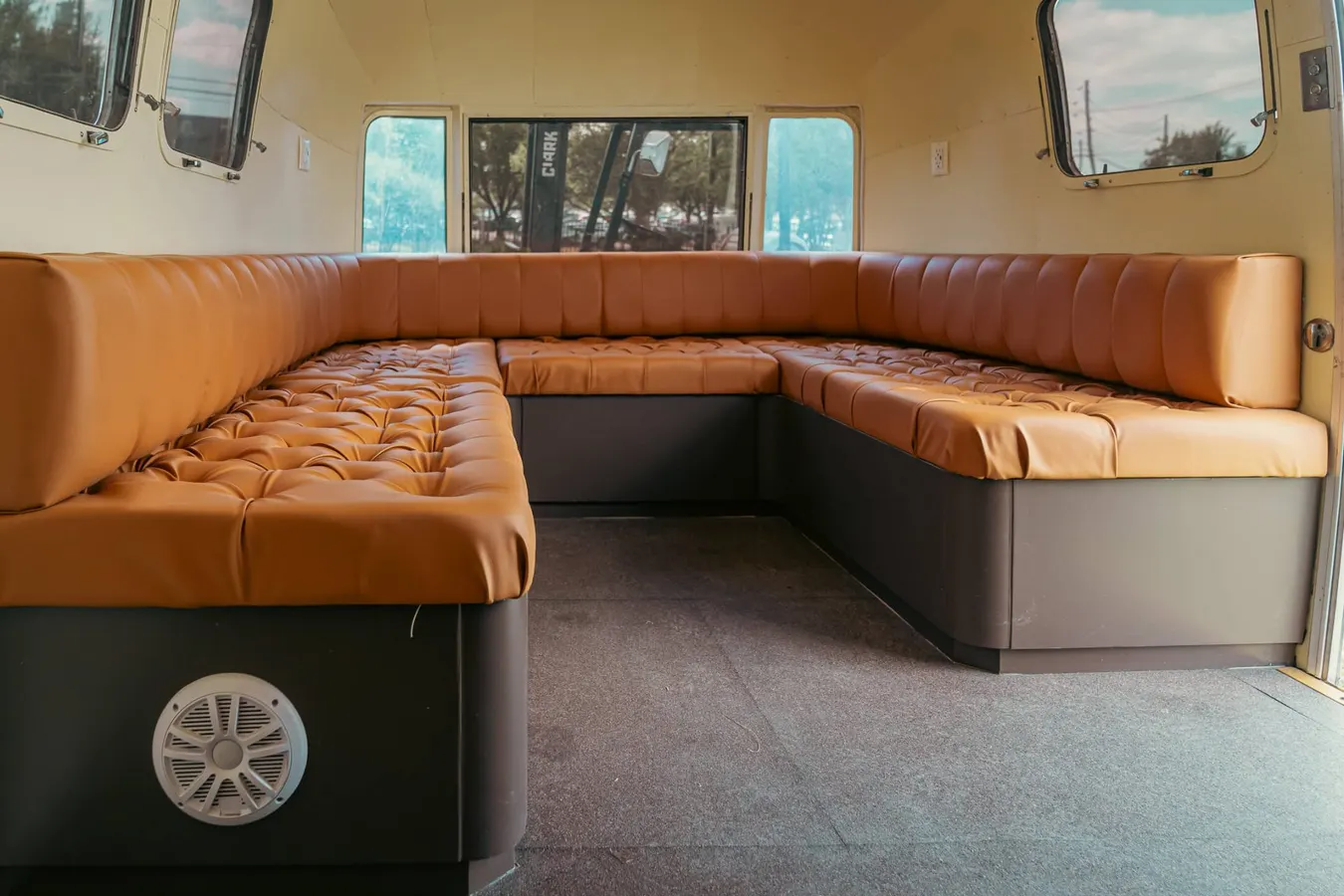 Tufted caramel leather U-shaped lounge seating inside the Airstream